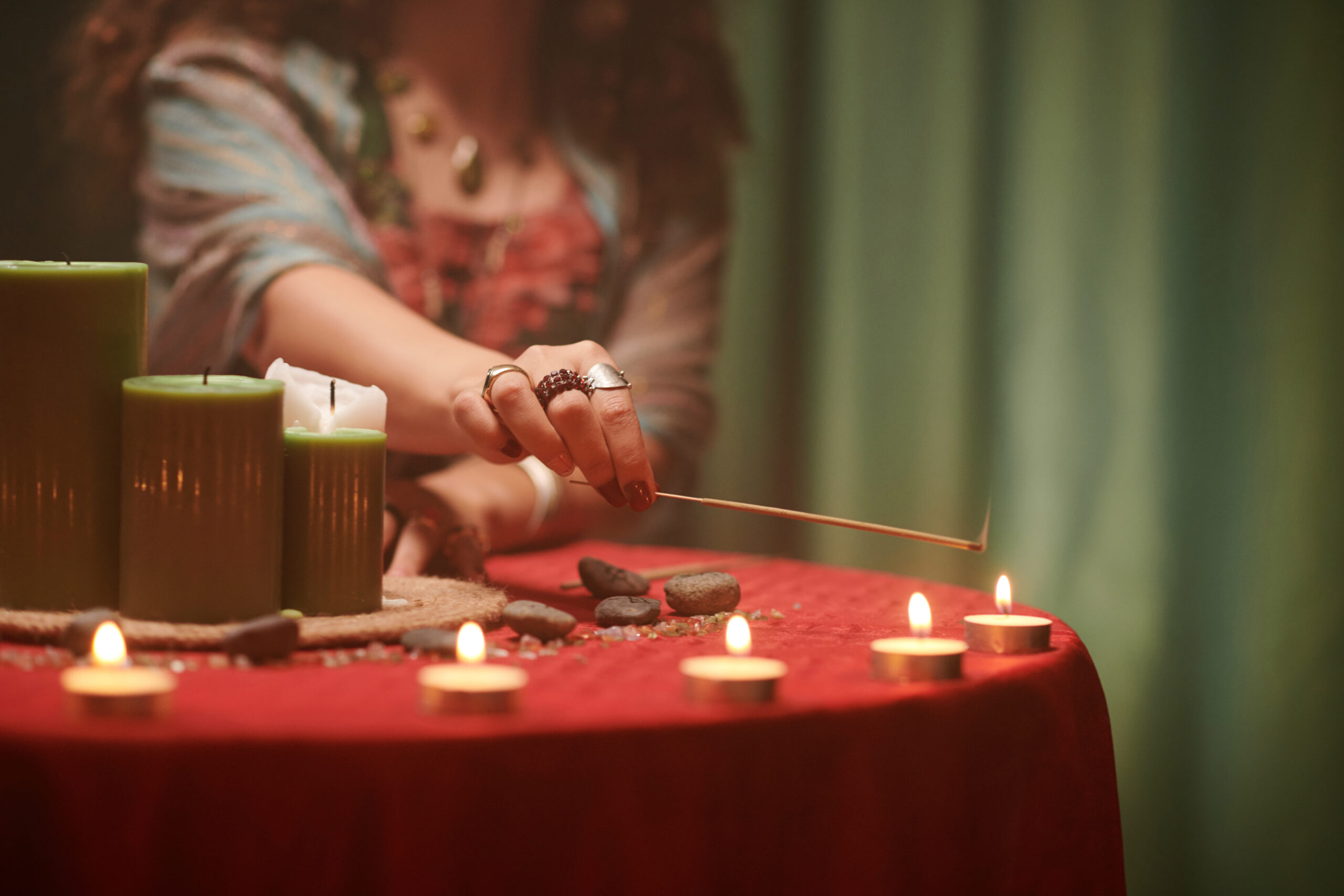 Closeup image of fortune teller burning candles on table before spreading cards