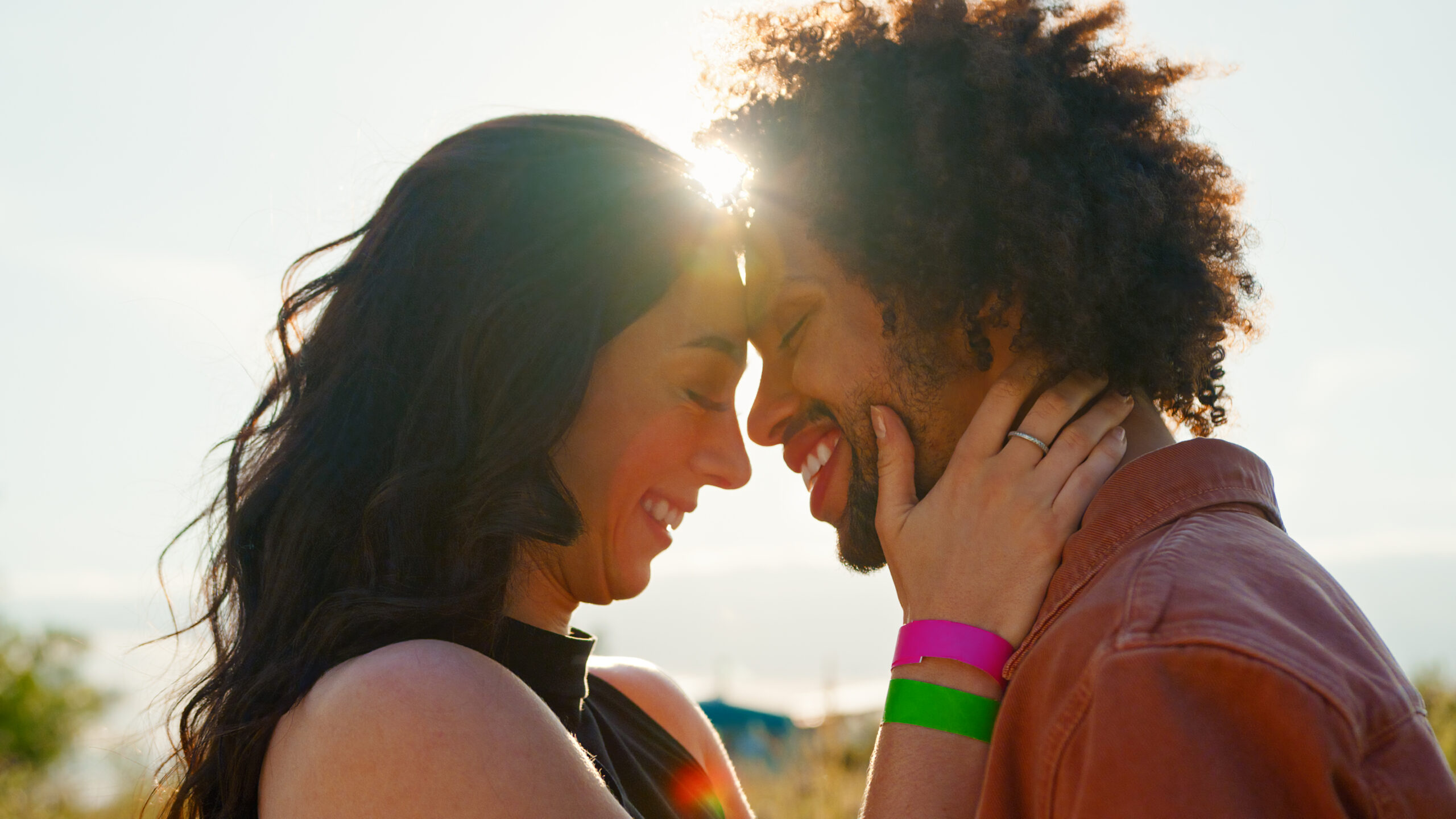Head And Shoulders Close Up Of Young Romantic Couple Hugging In Countryside Field With Setting Sun
