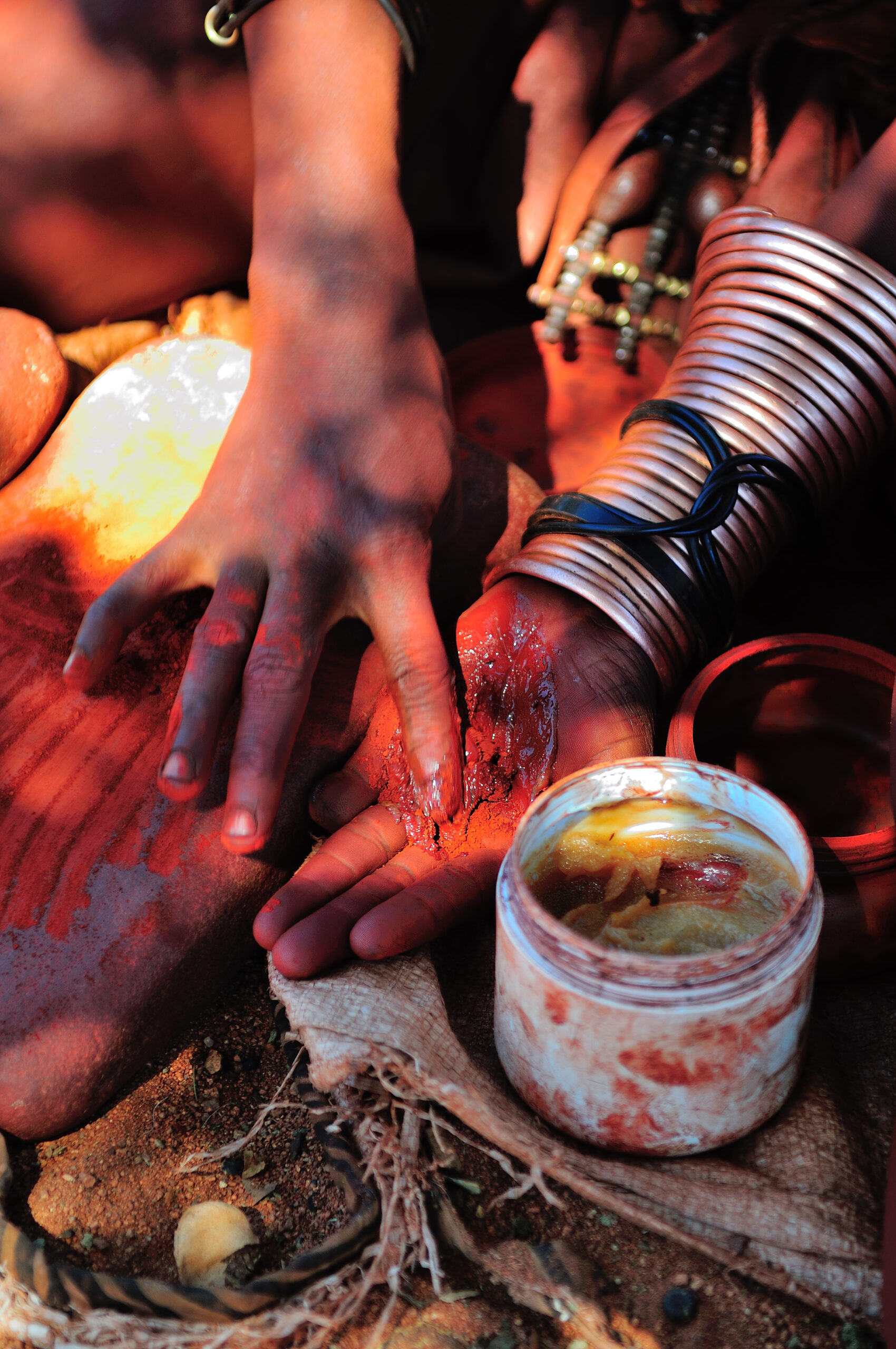 Himba woman mixing red ochre with petroleum jelly to apply to body. Traditionally it was mixed with animal fat.